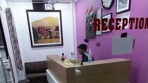 A reception area with a reception desk, a clock, framed pictures, and a 'Check in time' sign. - Hotel Prakash By GRB (Rishikesh)