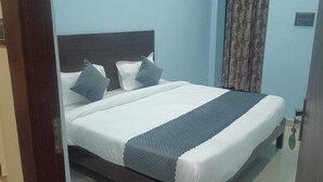 A neatly made bed with a dark headboard, white bedding, and a grey accent strip. - Hotel Prakash By GRB (Rishikesh)