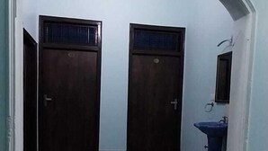 A room with two dark wooden doors, a blue sink, and a tiled floor. - Hotel Prakash By GRB (Rishikesh)