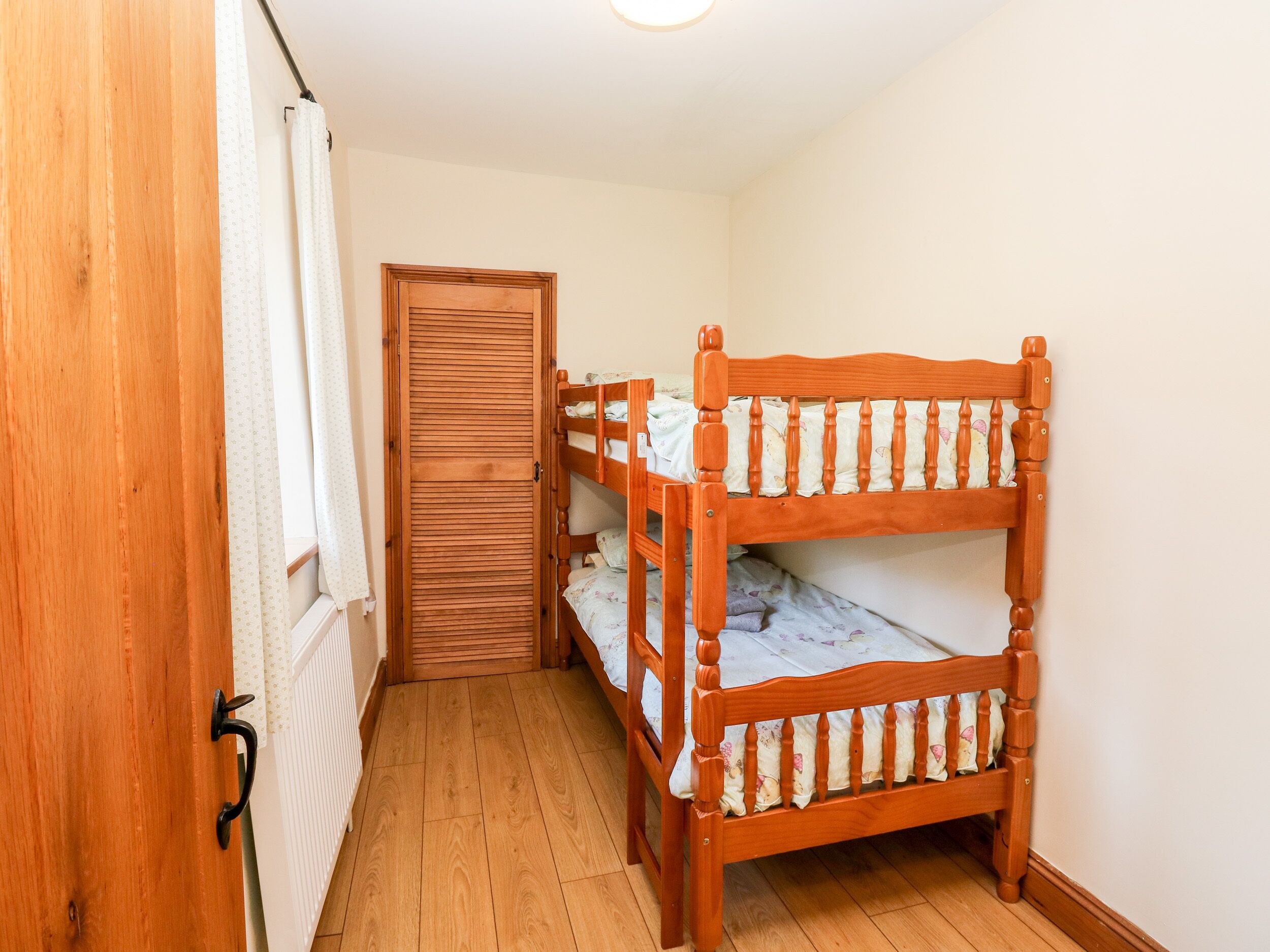 A wooden bunk bed in a room with a wooden door and a radiator.
