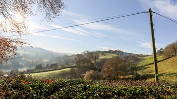 A rural landscape with rolling hills, a power line, and a clear sky.