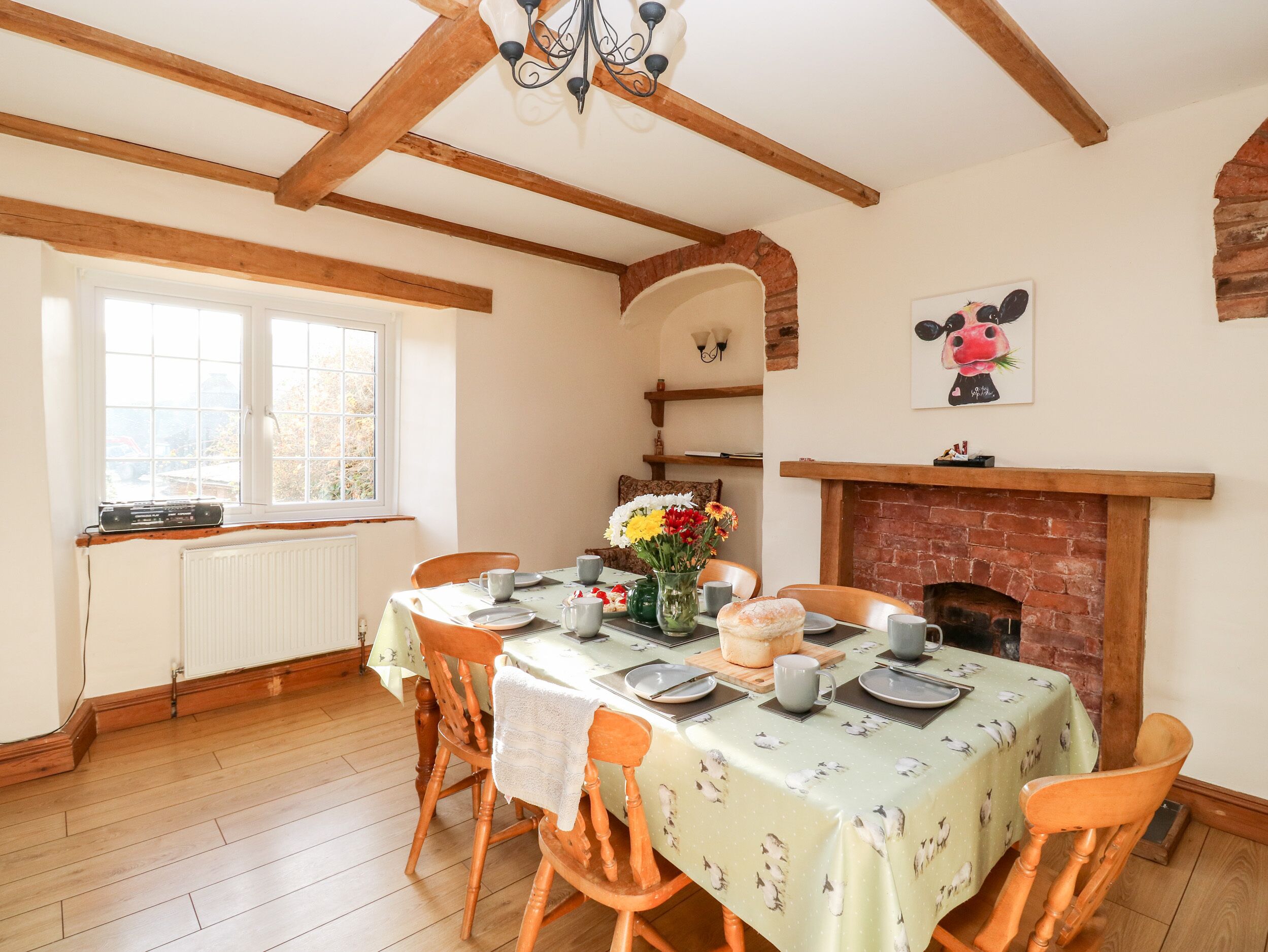 Comedor con una mesa lista para cuatro, chimenea y ventana con vistas.