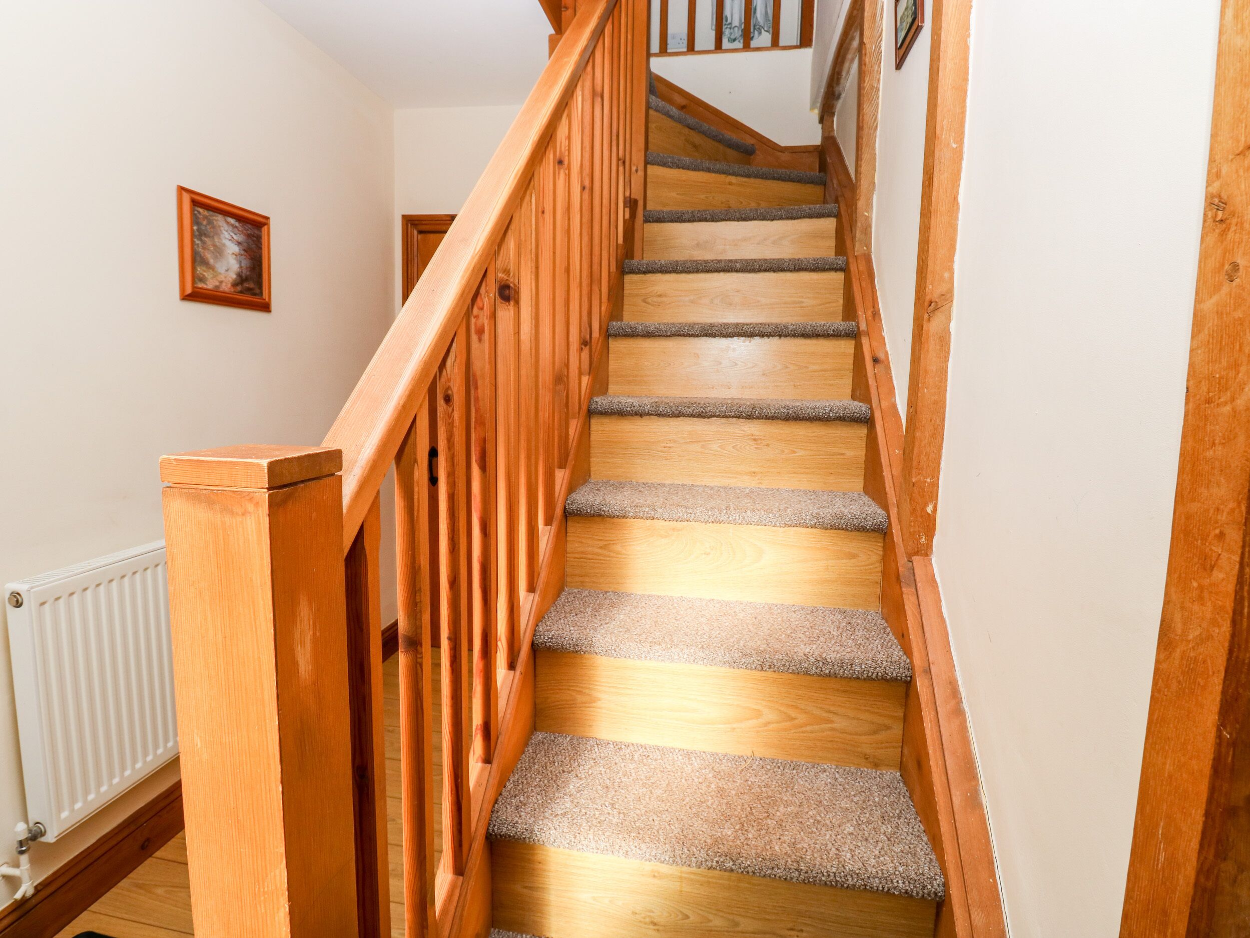 A wooden staircase with carpeted steps leading to a landing.