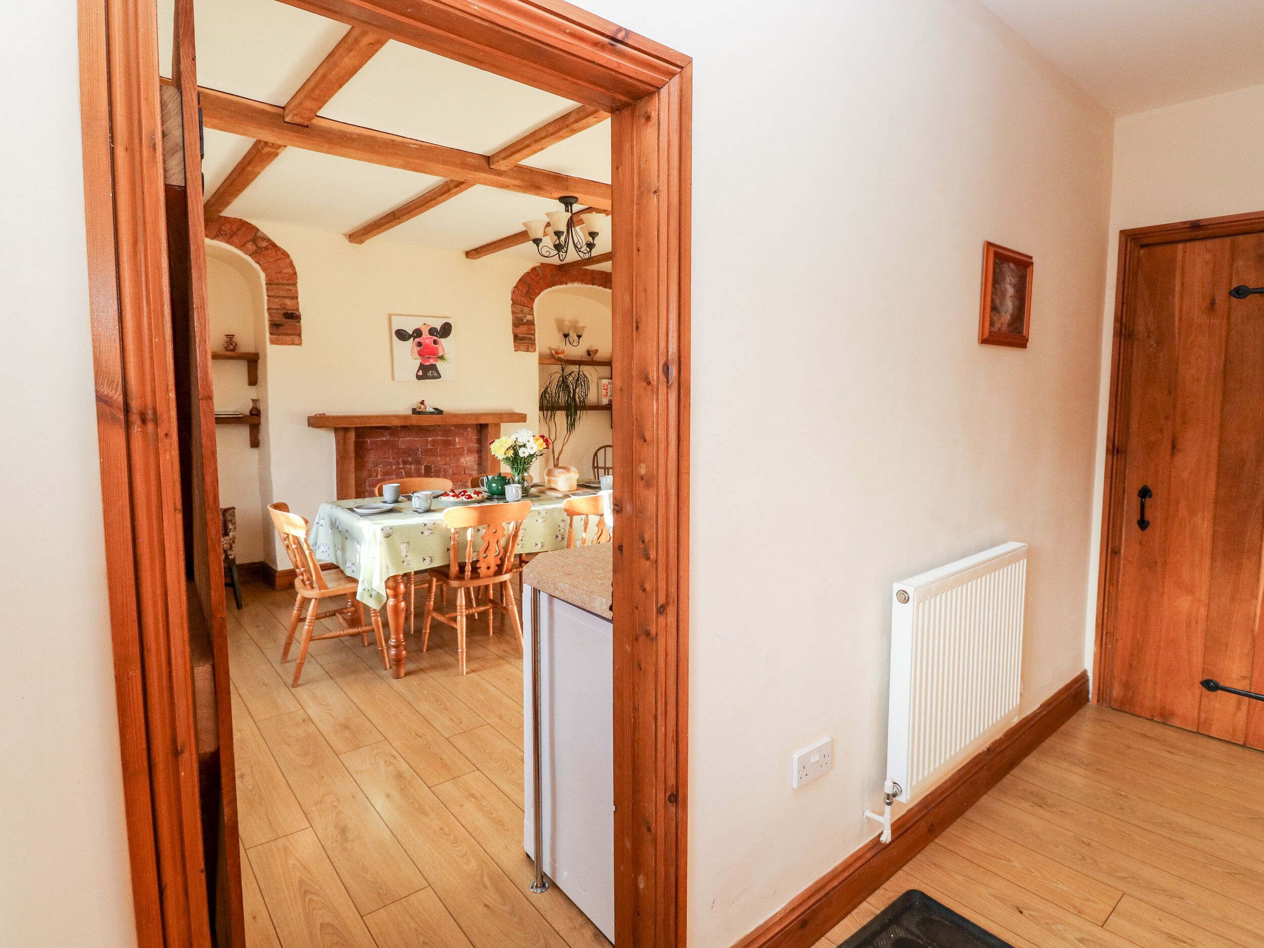 Comedor con estructura de madera, una mesa dispuesta para cuatro, un radiador y una puerta a la derecha.