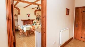 Comedor con estructura de madera, una mesa dispuesta para cuatro, un radiador y una puerta a la derecha.