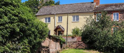 A traditional stone house with a sloped roof, a wooden front door, and a small porch.