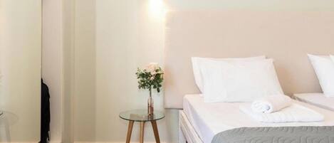 A hotel room with a bed, a small table with a vase of flowers, and a wall-mounted light.