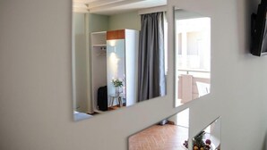 A hotel room with a large mirror, a wardrobe, a small table with a vase, and a fruit bowl. - Room in Guest Room - Girogiali Beach Hotel (Chania)