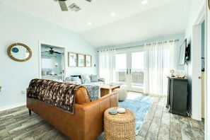 Un dormitorio amplio con una cama grande, ventilador de techo y vistas al exterior a través de una puerta corrediza de vidrio.