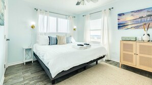 A bedroom with a bed, a ceiling fan, a nightstand, a cabinet, and a painting on the wall. - Cape Allswell - Life is Good, Sun, Sand & Surf! (Freeport)