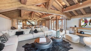 A spacious living area with a high wooden ceiling, a large sofa set, a coffee table, and a television. - Renovated chalet with pool, sauna and hammam for 14 people in Saint-Martin-de-Belleville (Saint-Martin-de-Belleville)