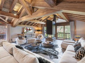 A spacious living area with a high ceiling, wooden beams, a fireplace, a television, and a view of the outdoors. - Renovated chalet with pool, sauna and hammam for 14 people in Saint-Martin-de-Belleville (Saint-Martin-de-Belleville)