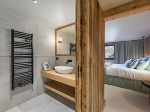 Une salle de bain moderne avec un meuble-lavabo en bois, un grand miroir et un porte-serviettes intégré.
