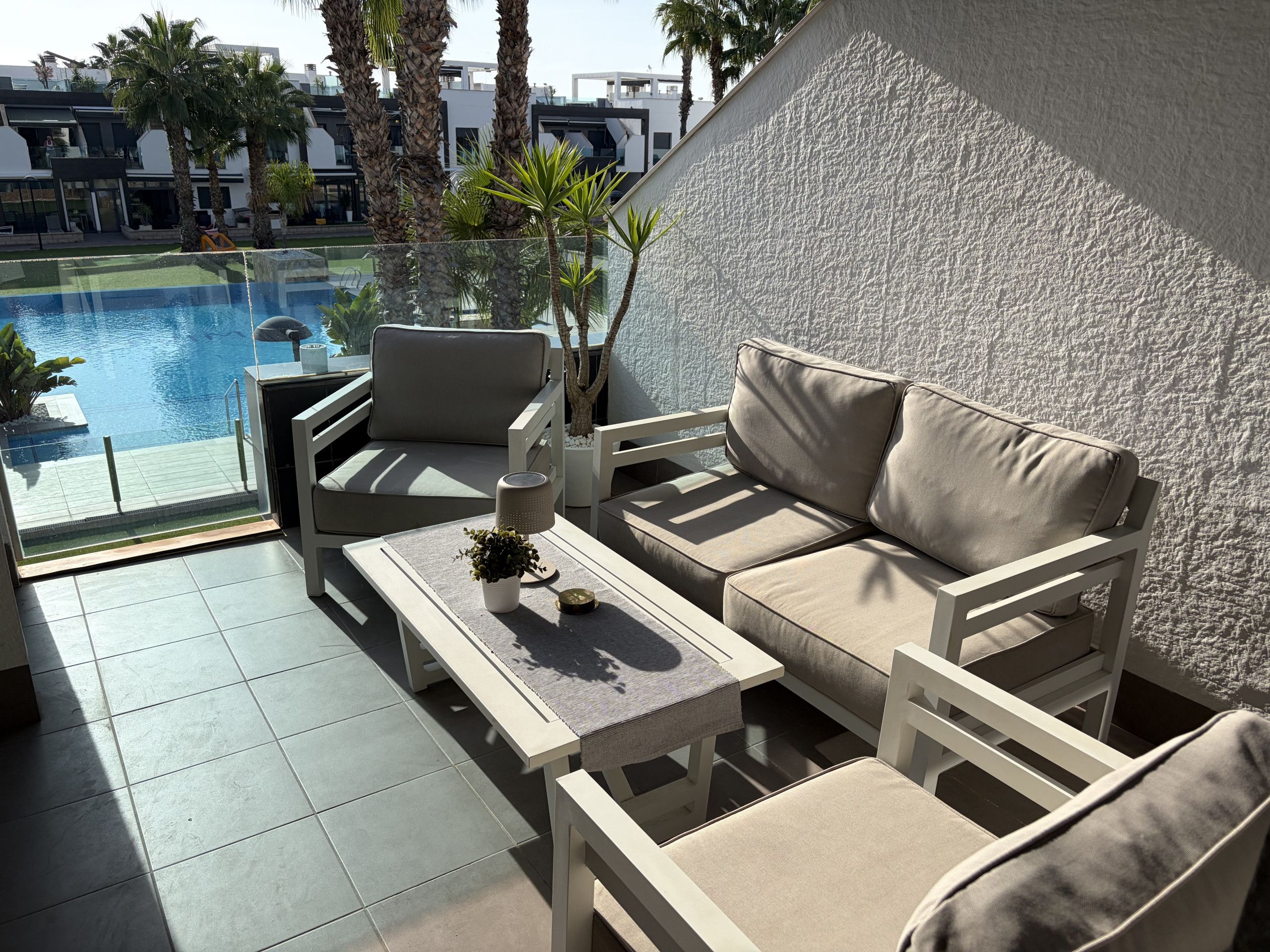 Un espace extérieur moderne aménagé pour se détendre, avec vue sur la piscine, comprenant un canapé, des fauteuils et une table.