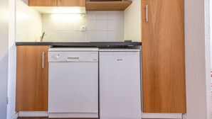 A compact kitchen with wooden cabinets, a microwave, and two white appliances, likely a dishwasher and a washing machine. - Apartment 5 ppl, 6th floor, WIFI, ski locker, La Plagne (Plagne Soleil)