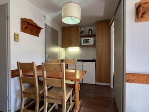 Una cocina funcional con armarios de madera, un microondas y una mesa con sillas.