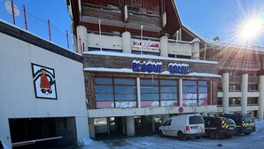 A building with a sign reading "PLAGNE SOLEIL" and "esf" logos. There are parked vehicles and a snow-covered ground. - Apartment 5 ppl, 6th floor, WIFI, ski locker, La Plagne (Plagne Soleil)