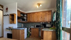 Eine kleine Küche mit Holzausstattung, einer Mikrowelle, einem Toaster und einem Spülbecken.