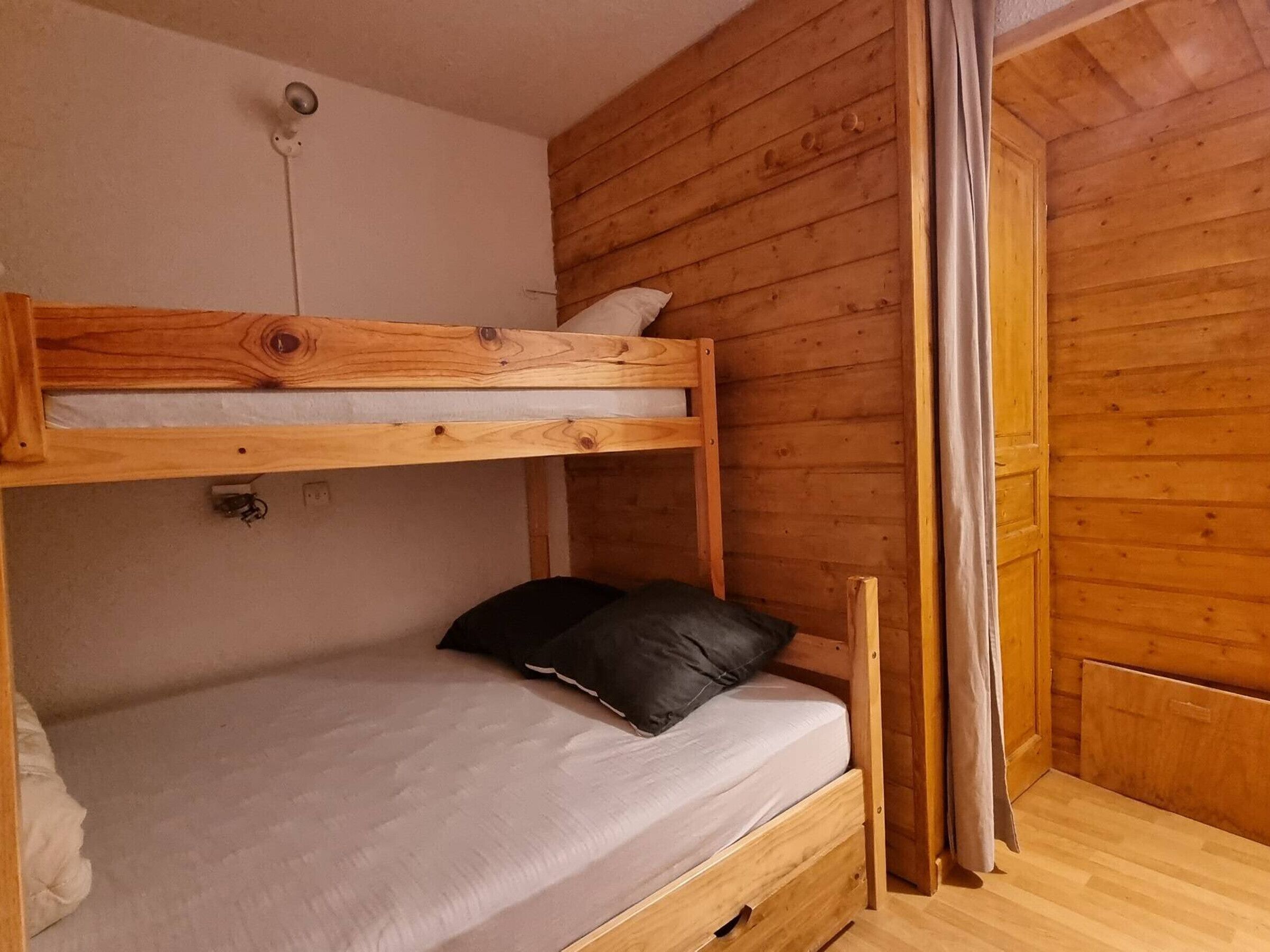 A bunk bed with a wooden headboard, a mattress, and a pillow.
