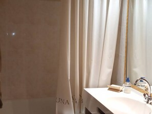 Bathroom features a large mirror, sink, and shower area with a shower curtain.