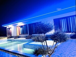 Enjoy a refreshing swim in the pool surrounded by a spacious deck and steps leading to the entrance of this modern building.