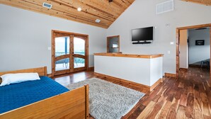 A bedroom with a wooden ceiling, a bed, a TV, and a large window. - NO bunk beds | Golf course & hill country views, private swimming pool, huge outdoor kitchen (Concan)