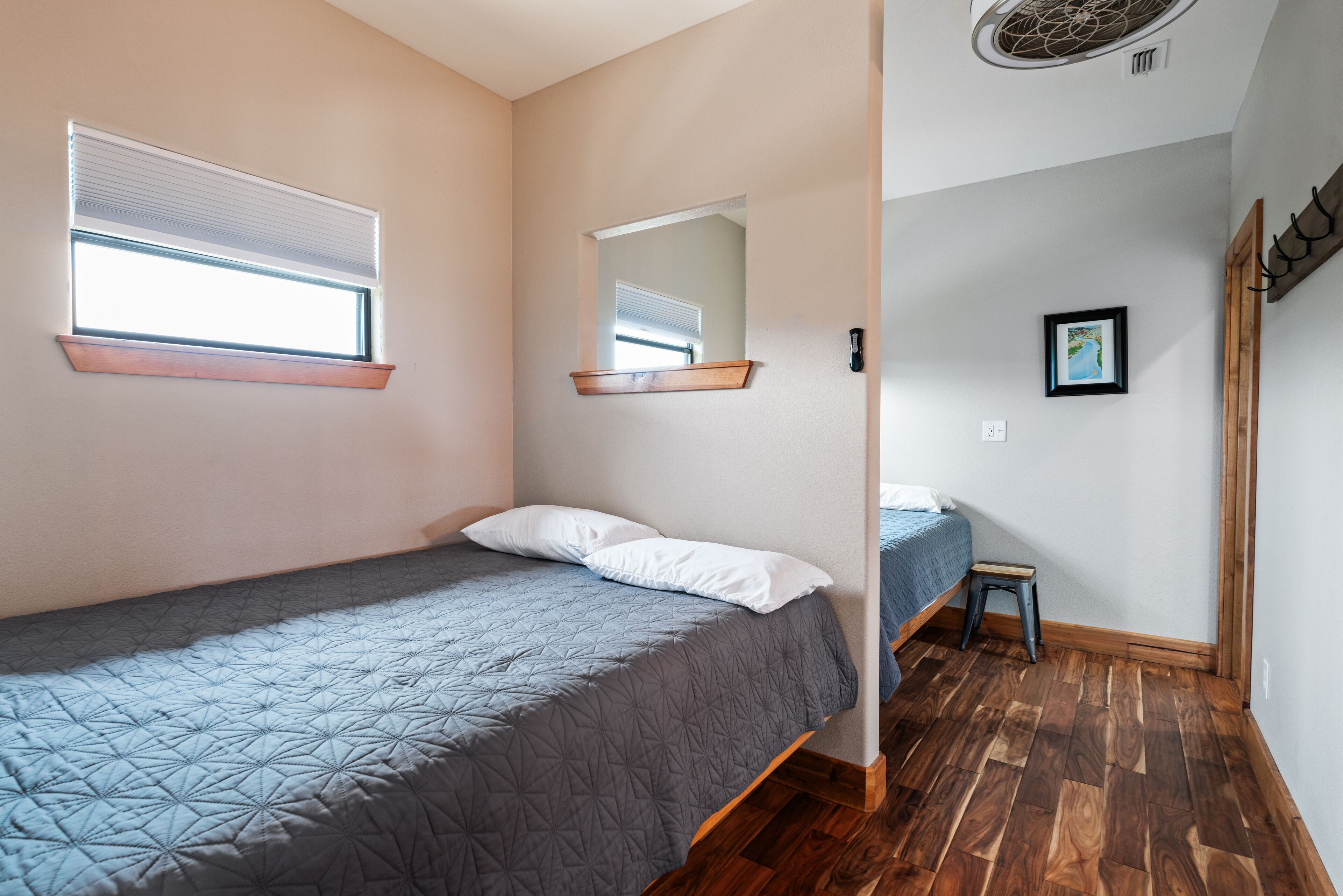 Un dormitorio con una cama individual, una ventana con persianas, un espejo y un taburete pequeño.