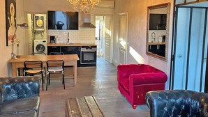 En kompakt opholdsstue med tekøkken, spiseplads og en rød sofa.