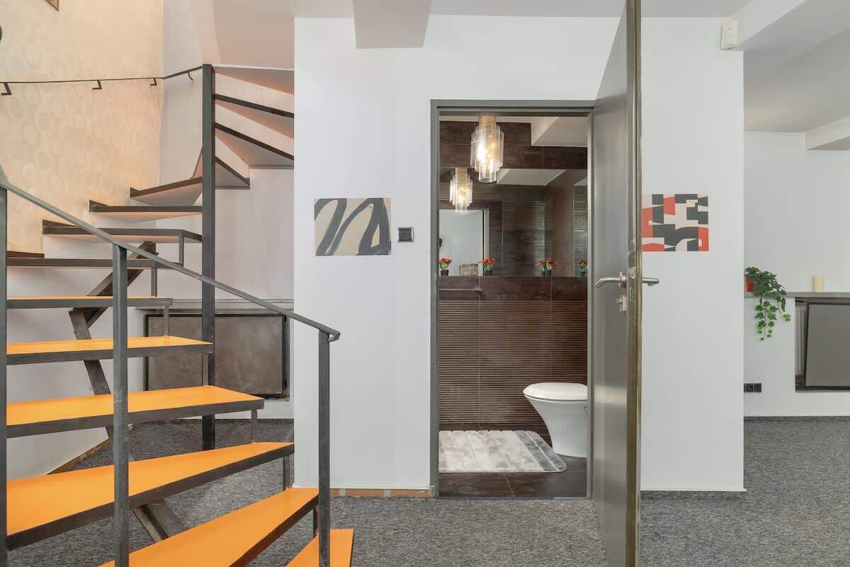 A modern interior with a staircase, a bathroom, and a door leading to another room.