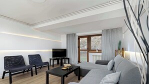 Un salon moderne comprenant un canapé, deux fauteuils, une table basse et un téléviseur.