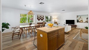 A spacious living area with a wooden dining table, a kitchen island, and a flat-screen TV. - Bohemian Condo Near Las Olas and Beach (Fort Lauderdale)