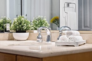 A bathroom with a sink, two faucets, a mirror, and a towel rack with folded towels. - Bohemian Condo Near Las Olas and Beach (Fort Lauderdale)