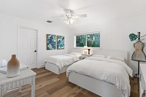 A bedroom with two beds, a ceiling fan, a window with blinds, and a dresser. - Bohemian Condo Near Las Olas and Beach (Fort Lauderdale)