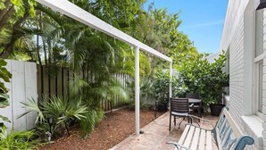 A patio with a white pergola, outdoor seating, and lush greenery. - Near Beach and Las Olas, 1 bedroom Apartment (Fort Lauderdale)
