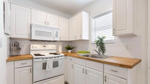 A kitchen with white cabinets, a microwave, stove, and a sink. - Near Beach and Las Olas, 1 bedroom Apartment (Fort Lauderdale)