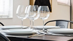 A dining table set with white plates, clear wine glasses, and silverware. - Chic Sailboat Bend Condo w/Parking, Near Riverwalk (Fort Lauderdale)