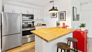 A modern kitchen with stainless steel appliances, a wooden island, and a red refrigerator. - Chic Sailboat Bend Condo w/Parking, Near Riverwalk (Fort Lauderdale)