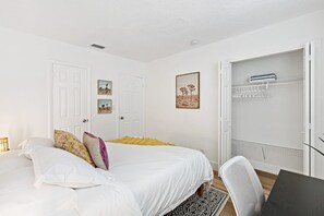 A bedroom with a bed, a desk, a chair, a wardrobe, and a door.