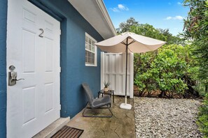 A house with a blue exterior, a white door, and a patio area with a chair and an umbrella. - Chic Condo w/ Patio, Near Fort Lauderdale Hotspots (Fort Lauderdale)