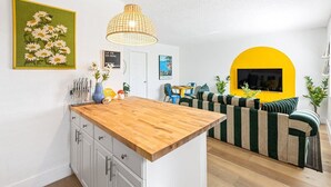 Et moderne køkken med en træø, lyse skabe og en hængende pendel.