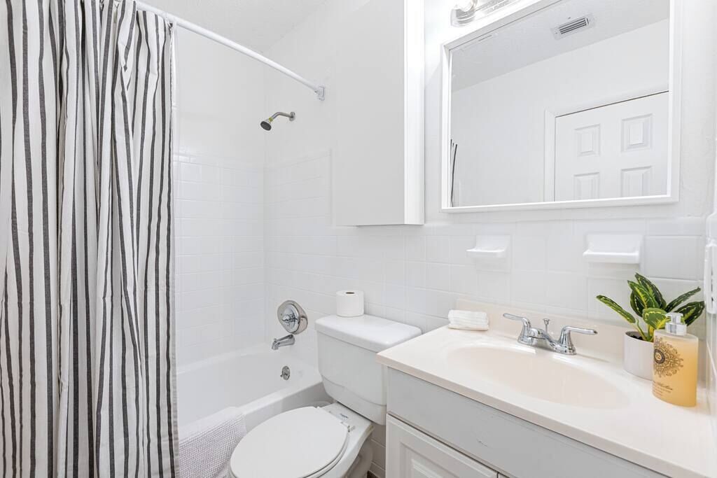 A modern bathroom with a shower, toilet, sink, and a mirror.