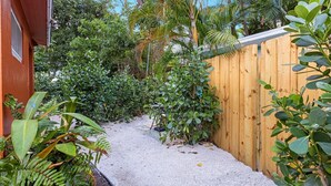 Un étroit sentier de gravier bordé d’une végétation dense et d’une clôture en bois.