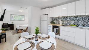 Une cuisine moderne avec des meubles blancs, un pare-feu décoré et un coin repas doté d’une table ronde pour quatre personnes.