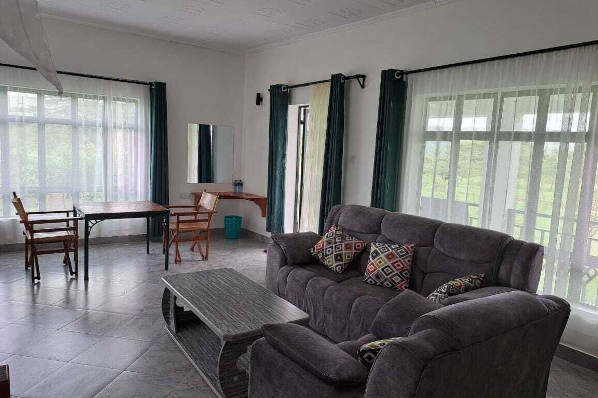 Una sala de estar con un sofá gris, una mesa de centro de madera y una mesa de comedor con sillas.