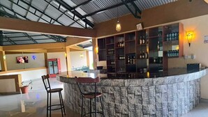 A bar area with a stone counter, two bar stools, and shelves with bottles. - Iretet Mara Lodge (Maasai Mara)