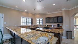 A spacious kitchen with a large island, built-in appliances, and ample natural light from windows. - Spacious Golf Course Retreat on Hogan (Lake Havasu City)