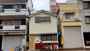 Un bâtiment avec une porte de garage fermée, un vélo garé devant et une petite pancarte sur le mur.