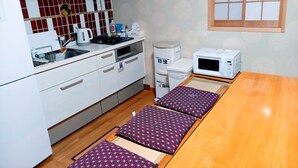 Une cuisine compacte avec des meubles blancs, un four à micro-ondes, une bouilloire et une poubelle.