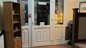 A room with a wooden cabinet, a striped carpet, and a door with a 'No Vacancies' sign. - The Singlecote Hotel (Skegness)