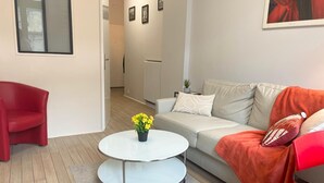 Ein modernes Wohnzimmer mit einem roten Sessel, einem weißen Sofa, einem runden Couchtisch mit gelben Blumen und einem grauen Teppich.